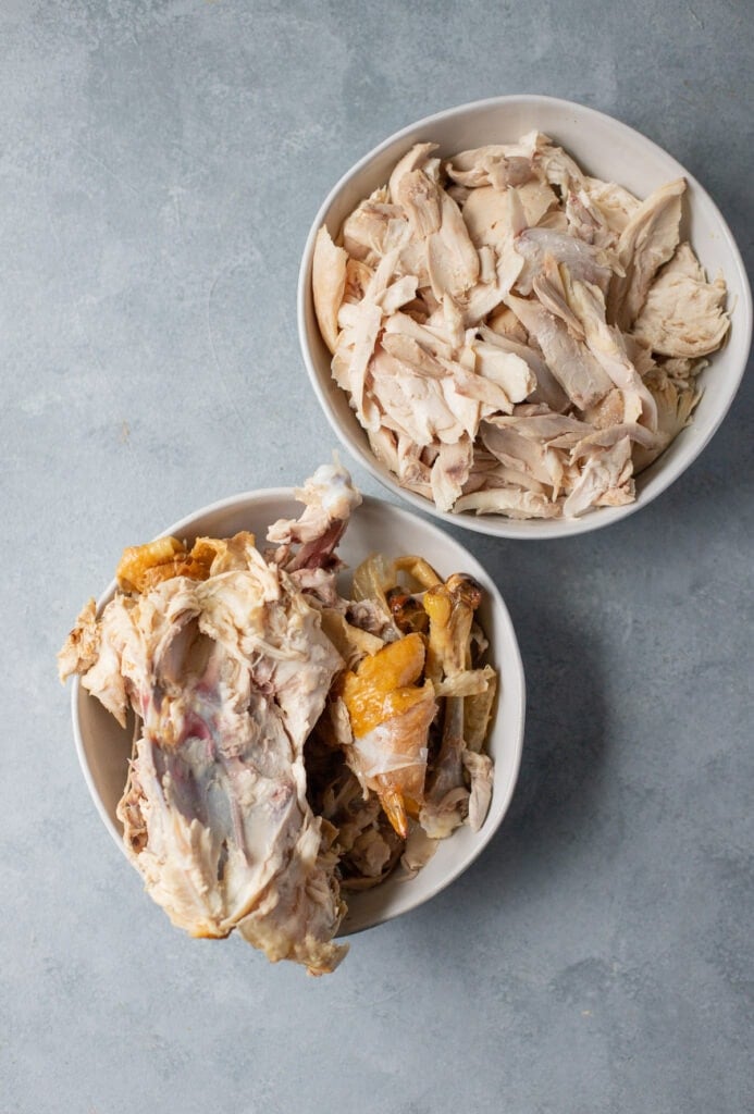 Ingredients needed to make homemade chicken broth: chicken and bones in two bowls