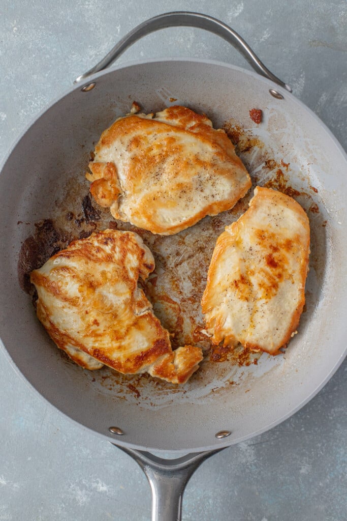 Chicken breasts searing in a pan for chicken cacciatore