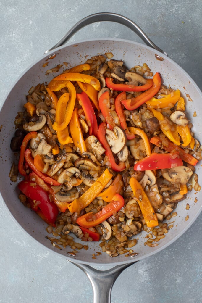 Onions, garlic, mushrooms and peppers cooking in a pan for chicken cacciatore