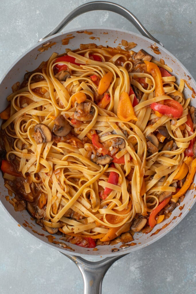 Fettuccine noodles tossed in veggies and sauce in a pan for chicken cacciatore 