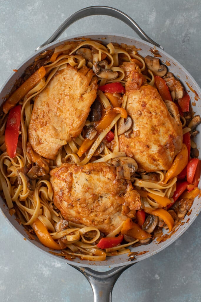 Chicken cacciatore in a pan on a grey background