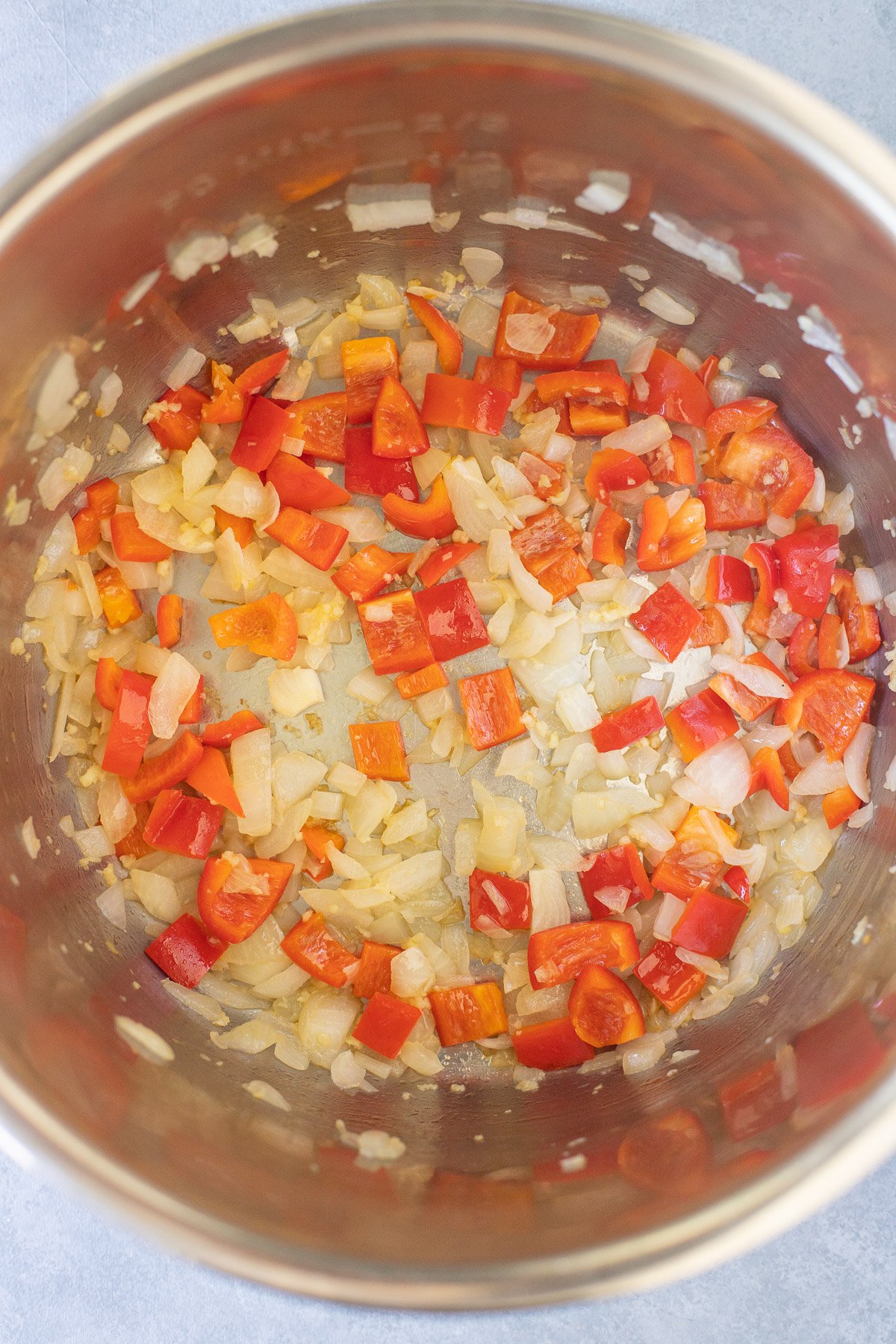 Onions and peppers sautéing in an instant pot base for chicken enchilada soup