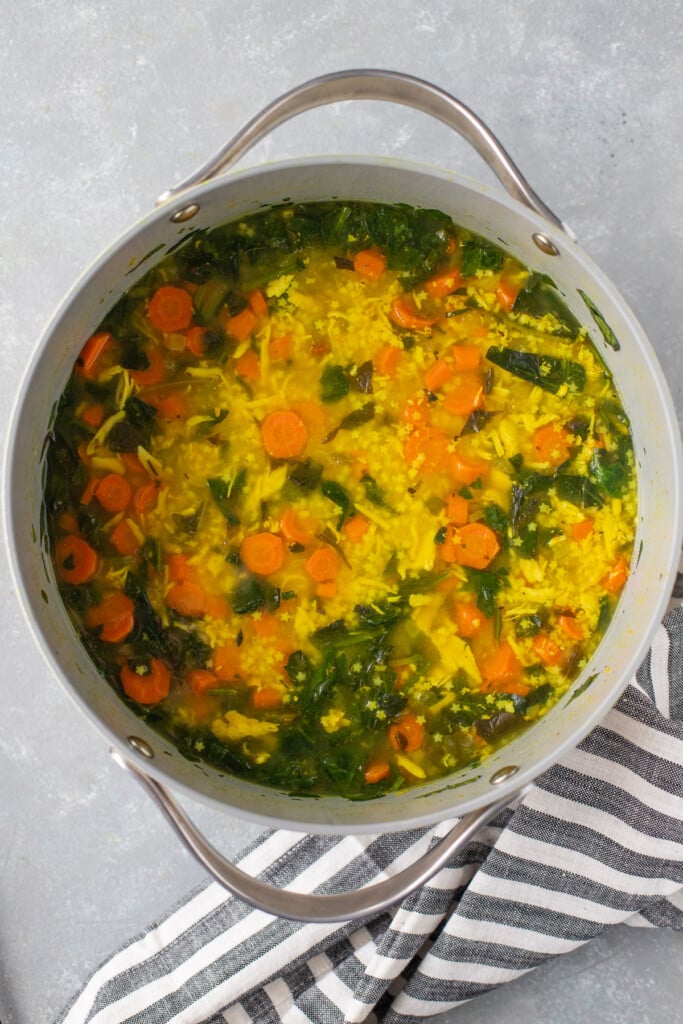 Chicken pastina soup in a grey pot on a grey counter