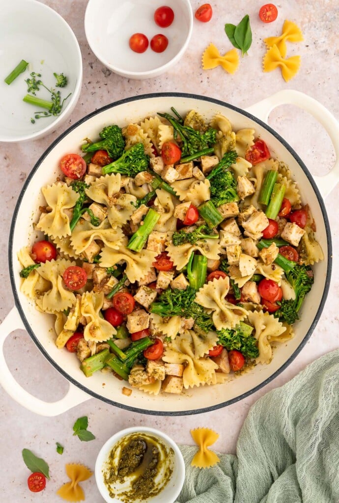 An overhead shot of a dutch oven with chicken veggie pasta with empty ingredient bowls on the side.