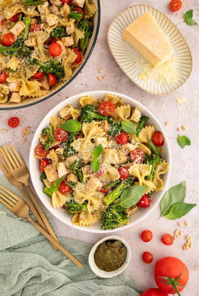 A large bowl of chicken pesto pasta with a dutch oven of the pasta on the side.