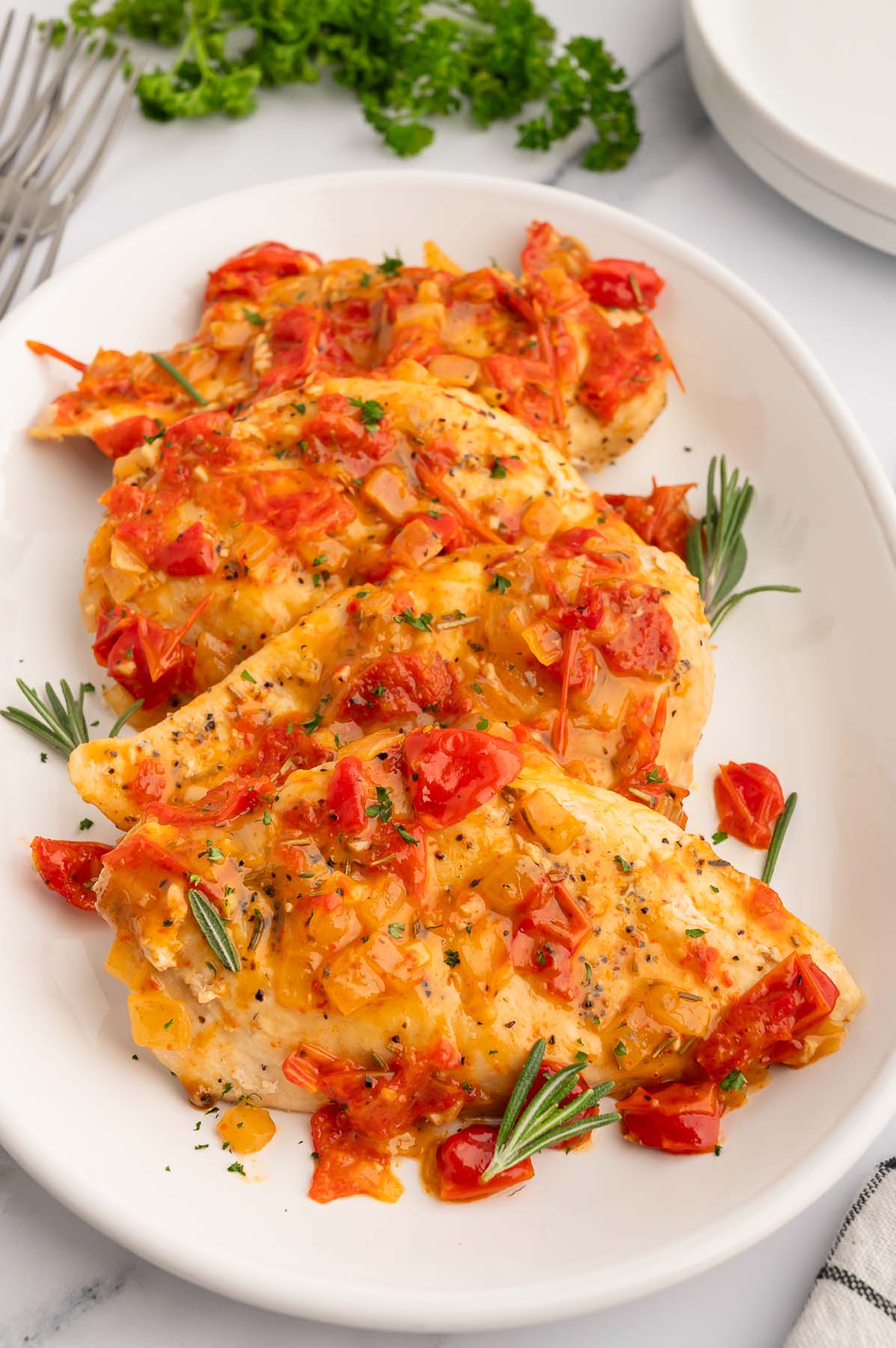 Chicken Scarpariello on a white platter on a white counter.