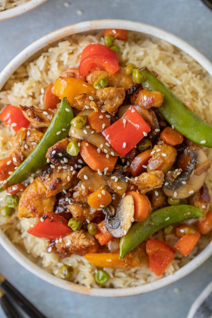 Chicken Stir Fry on a bed of rice in a bowl on a grey background