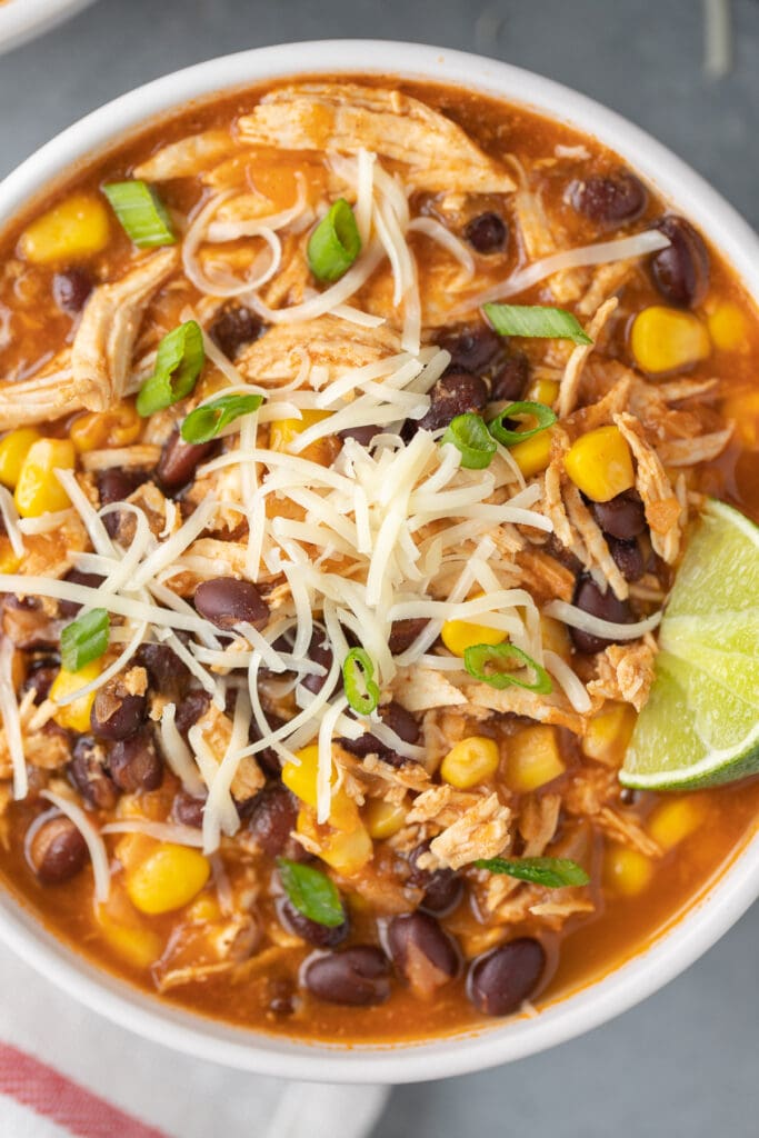A close up of a bowl of chicken taco soup with a lime on it