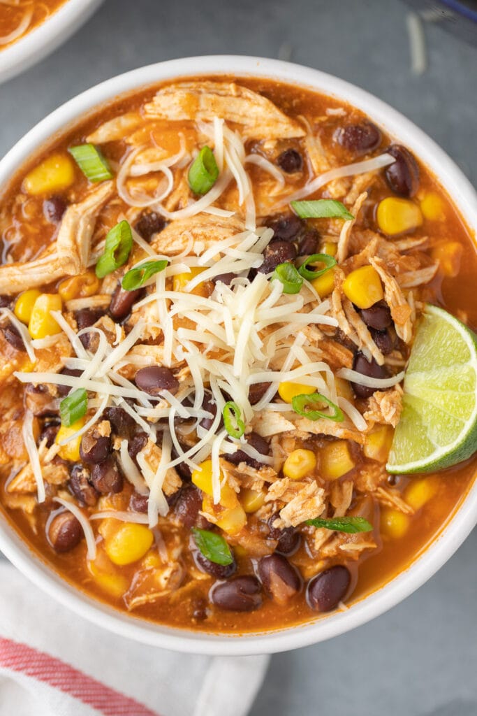 A close up of a bowl of chicken taco soup with a lime on it