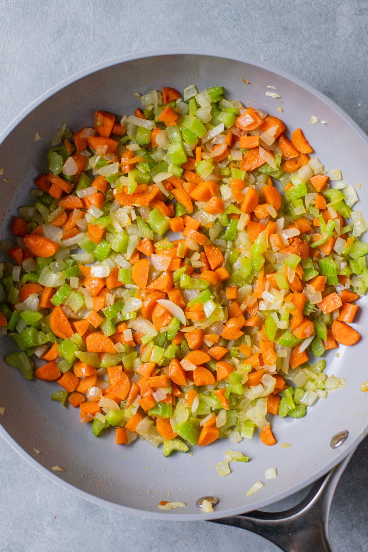 Sautéd celery, onion, carrots, garlic, and spices in a pan for chicken and wild rice soup
