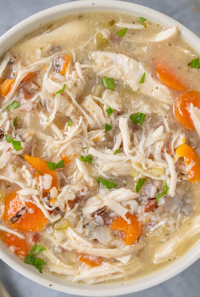 A close up shot of a white bowl of chicken and wild rice soup