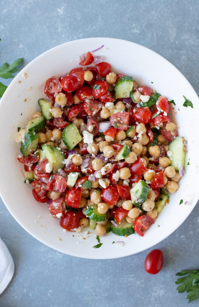 A greek chickpea salad in a large white bowl on a grey background