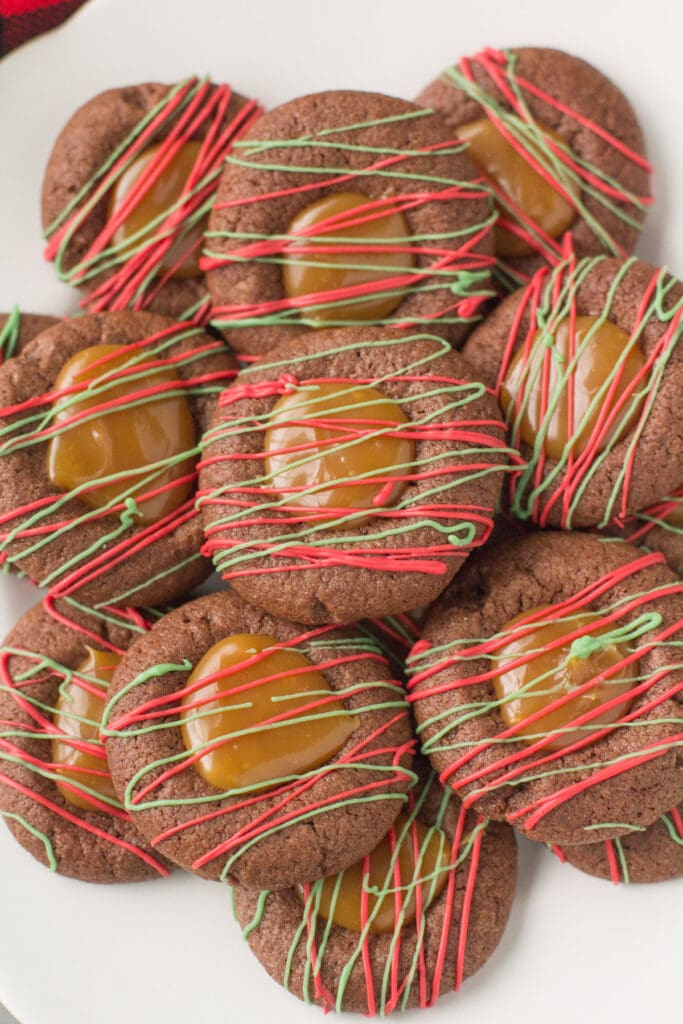 Chocolate Caramel Thumbprint Cookies drizzled with christmas colored chocolate on a white plate