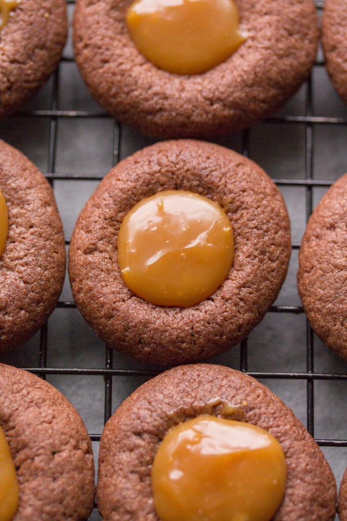 A close up of Chocolate Caramel Thumbprint Cookies on a cooling rack