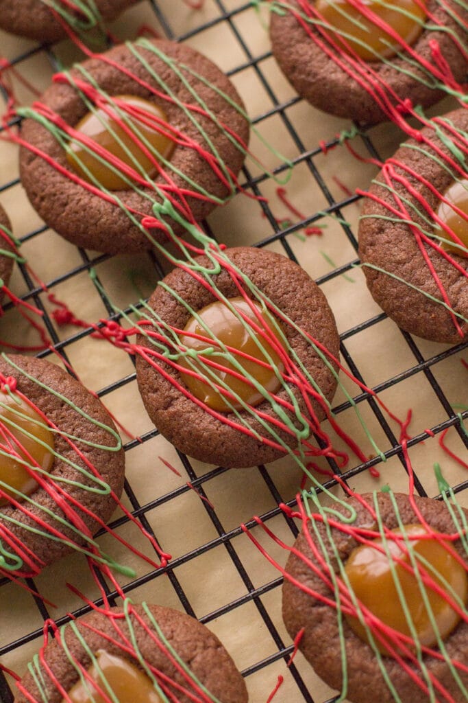 Chocolate Caramel Cookies drizzled with colored chocolate on a cooling rack