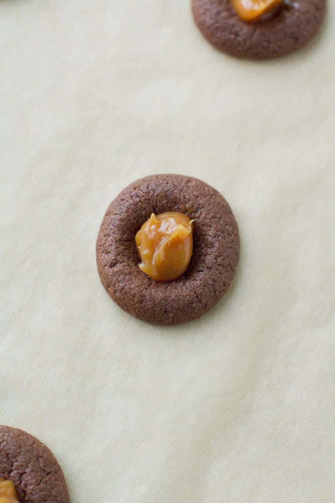 chocolate caramel thumbprint cookies with caramel dropped in the middle before being baked