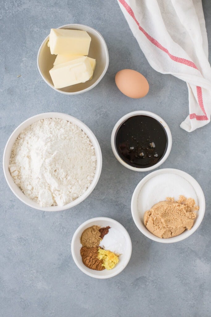Ingredients for Crispy Gingersnap Cookies in small white bowls on a grey background