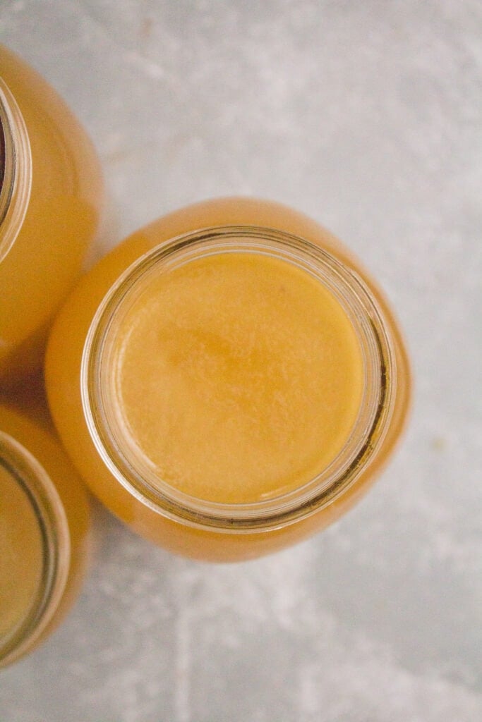 An overhead shot of Easy Crockpot Bone Broth in a glass mason jar on a glass background