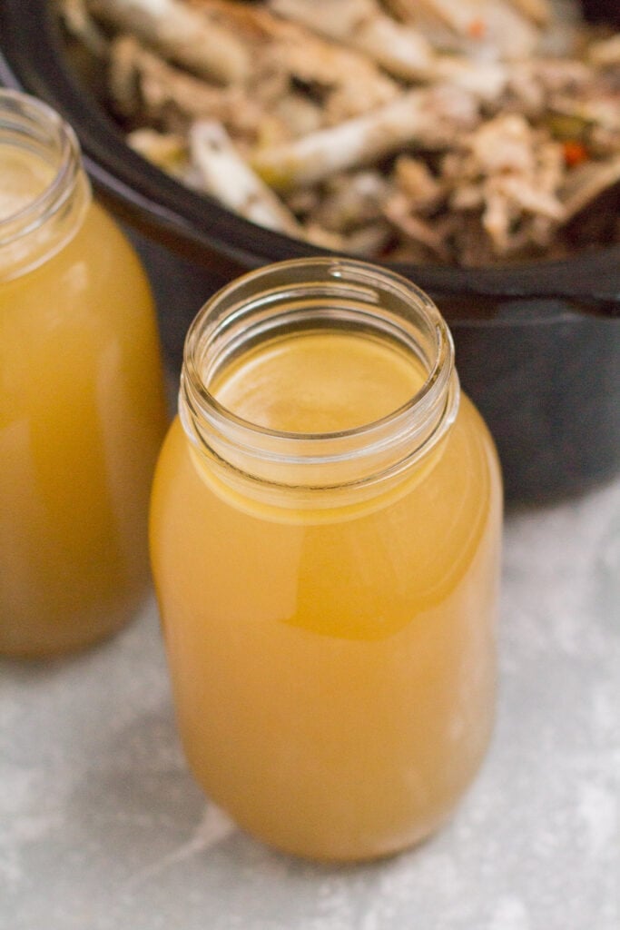 A glass of bone broth in front of a crockpot
