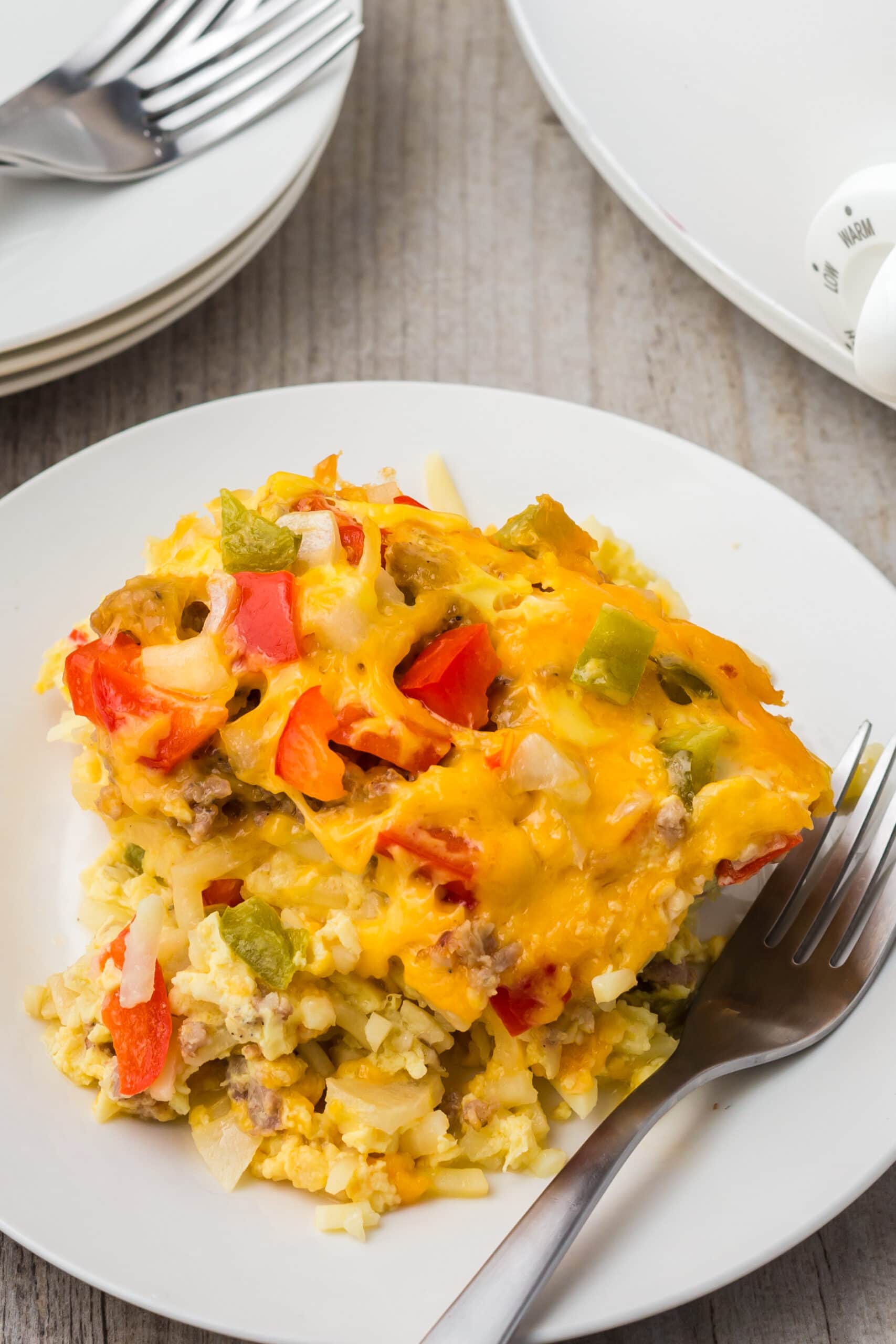 A piece of crock pot breakfast casserole on a white plate with a fork on the side