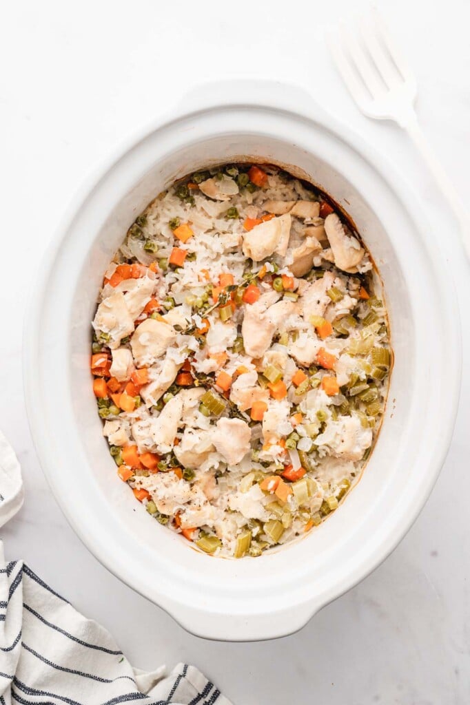 Crockpot Chicken and rice in a white slow cooker base on a white background.