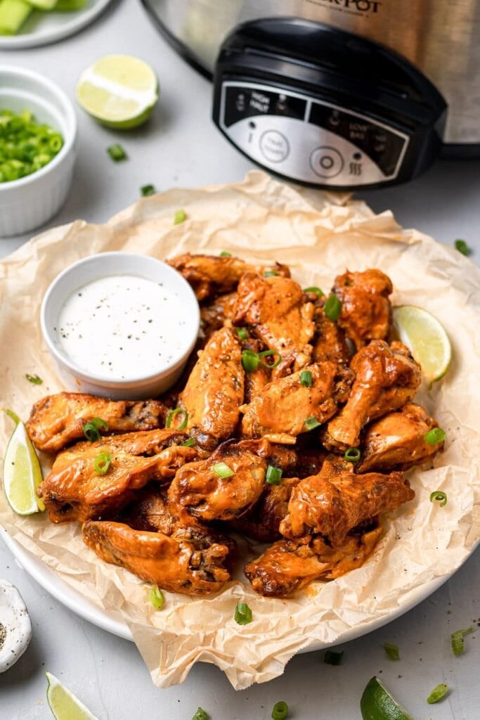 Crockpot Chicken Wings on a platter with a slow cooker in the background