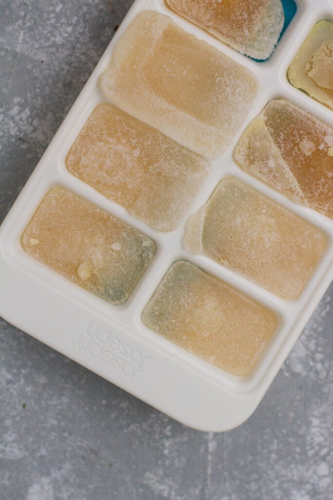 Bone broth frozen in ice cube trays on a grey background