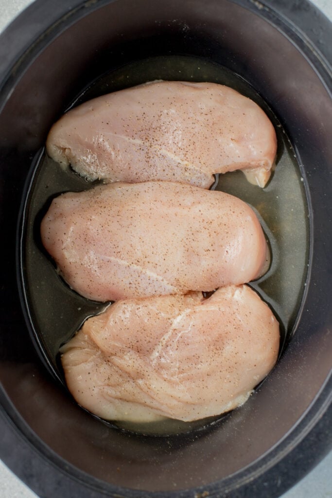 Raw Chicken breasts in a crockpot before being cooked for slow cooker shredded chicken