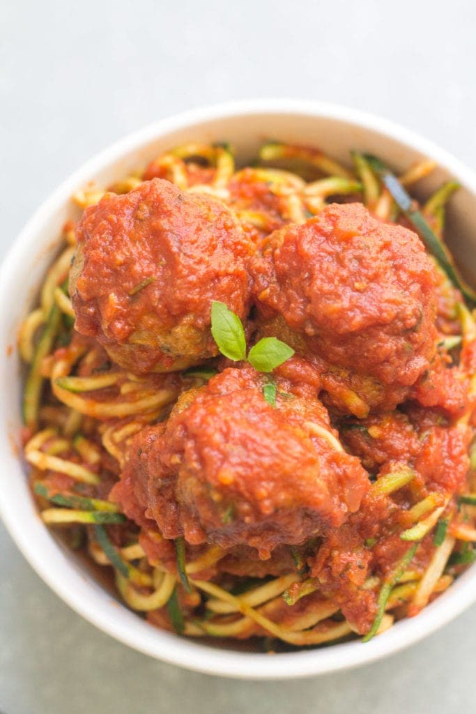 a bowl of meatballs over zoodles with crockpot tomato sauce on top.