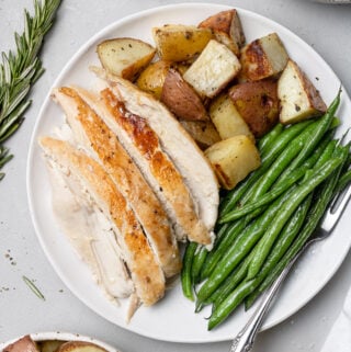 an overhead shot of Crockpot Whole Chicken sliced on a white plate with veggies and potatoes