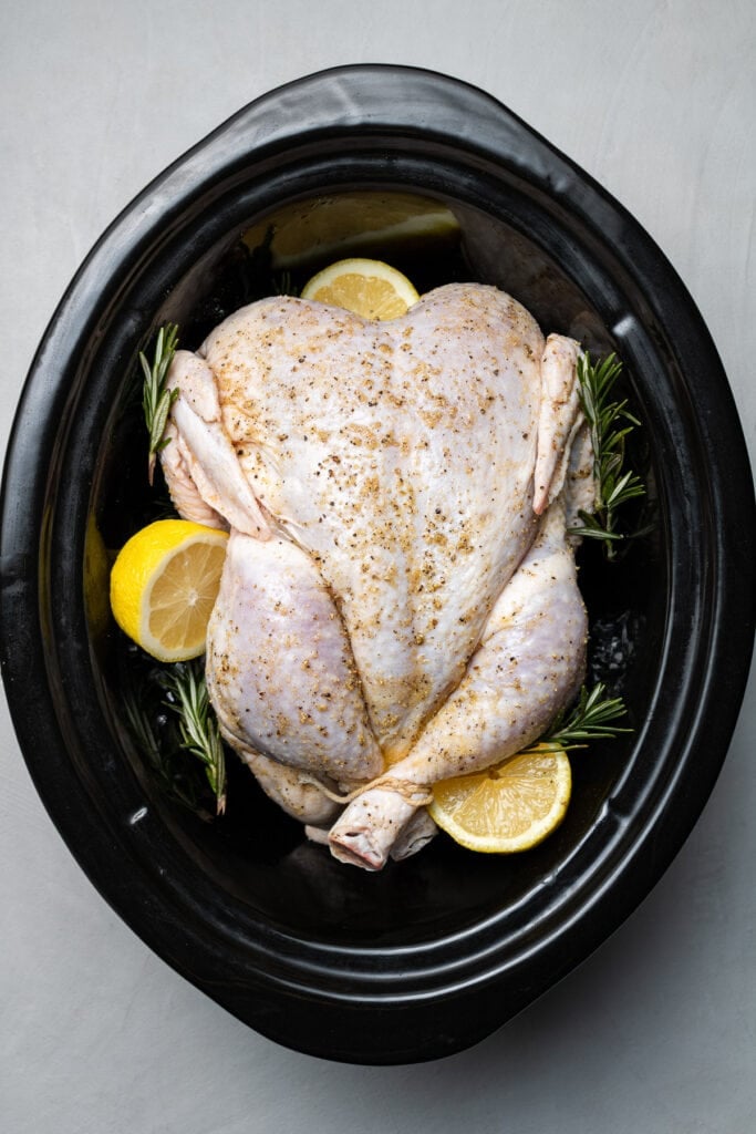 A raw whole chicken in the slow cooker before being cooked