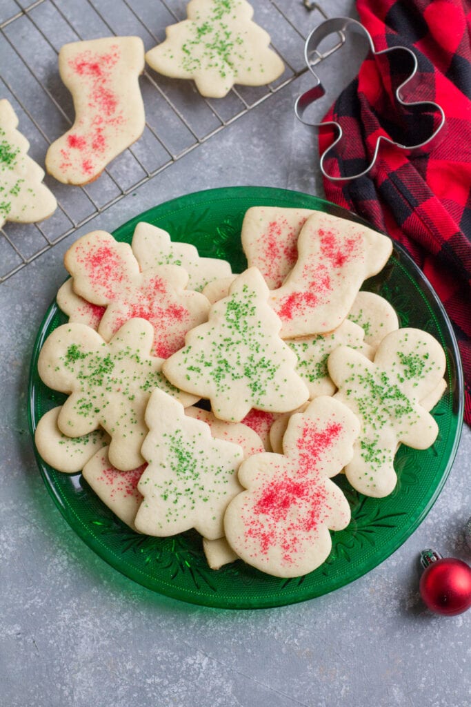 Classic Sugar Cookies on a green plate with a cooling rack and linen off to the side