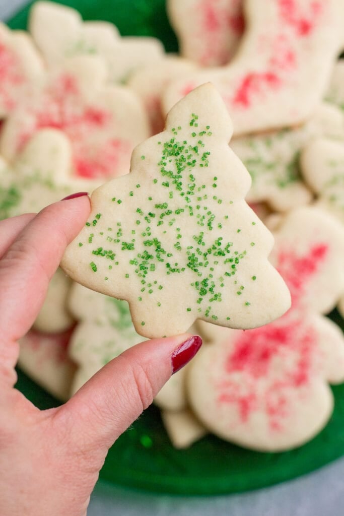 A hand holding up a christmas sugar cookie cut out