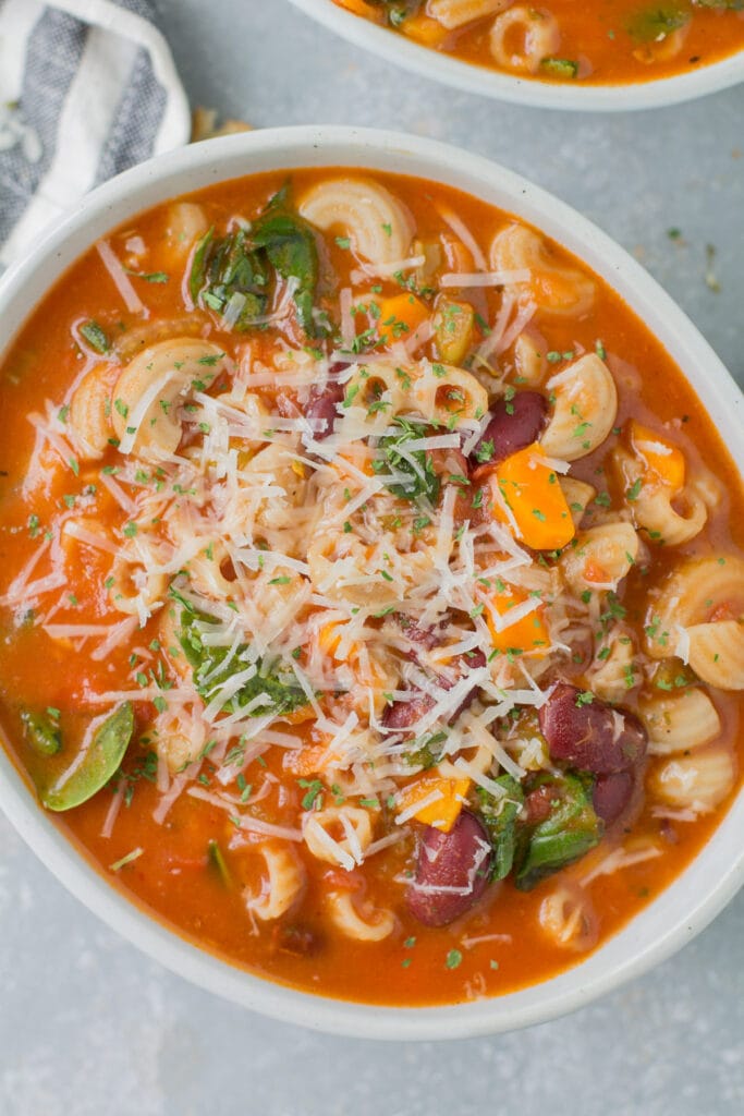 An overhead shot of Easy Minestrone Soup in white bowl on a grey background