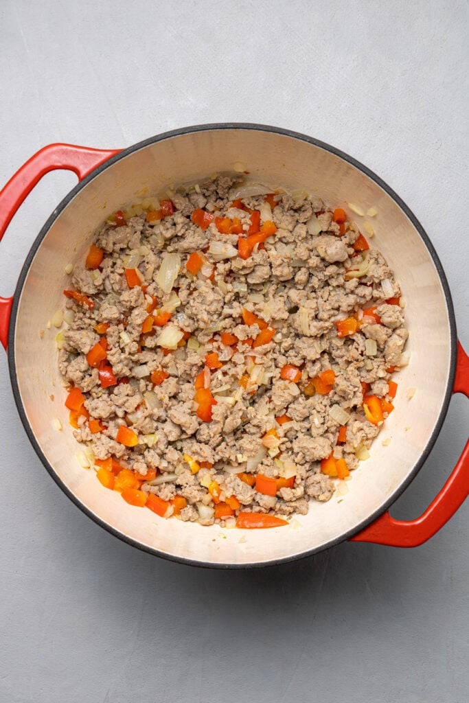 Browned sausage, onions, garlic, and peppers in a pot for egg hash brown casserole