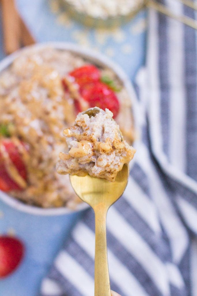 A gold spoon holding up a spoonful of egg white oatmeal.