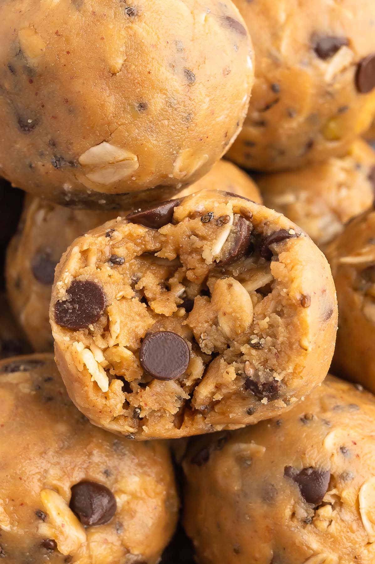 a peanut butter oatmeal ball with a bite taken out of it surrounded by more energy balls