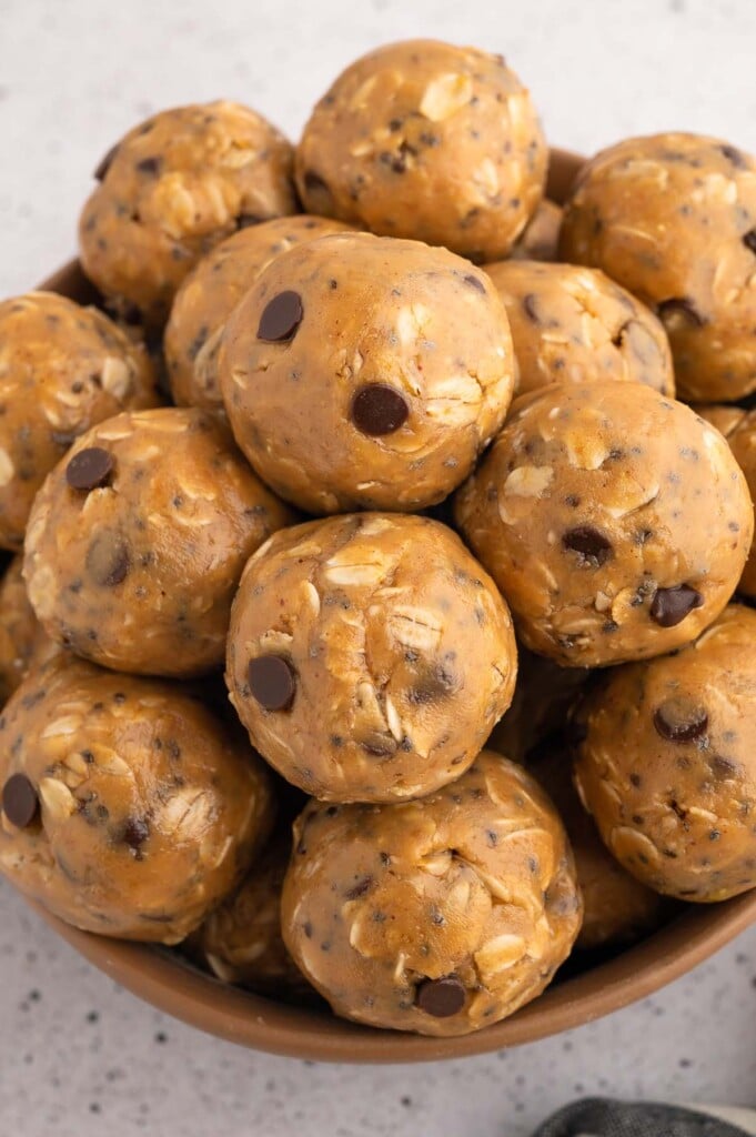 A stack of peanut butter energy bites in a bowl on a grey background