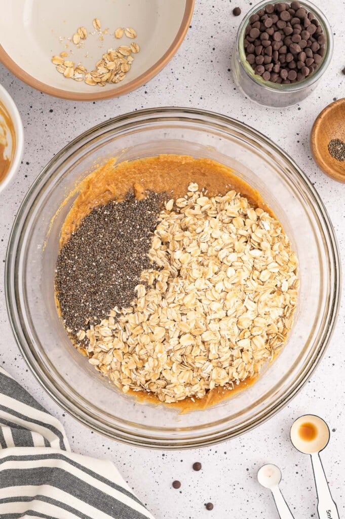Oats and chia seeds on top of a peanut butter mixture before being mixed in to make energy balls