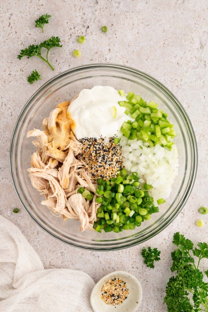 All ingredients for everything bagel chicken salad in a clear bowl before mixing.