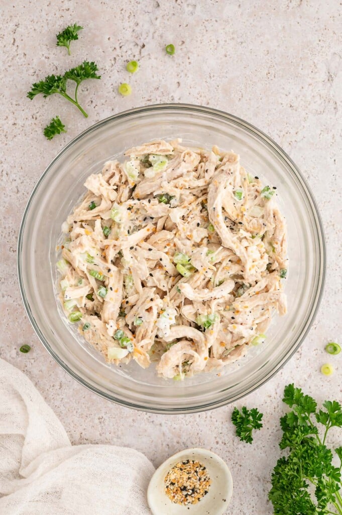 Everything bagel chicken salad in a clear bowl with a small bowl of leftover seasoning on the side.