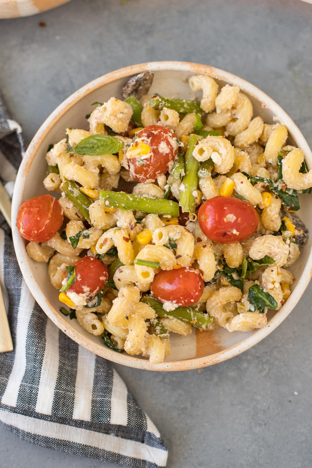 A close up of a bowl of baked feta pasta on a grey background
