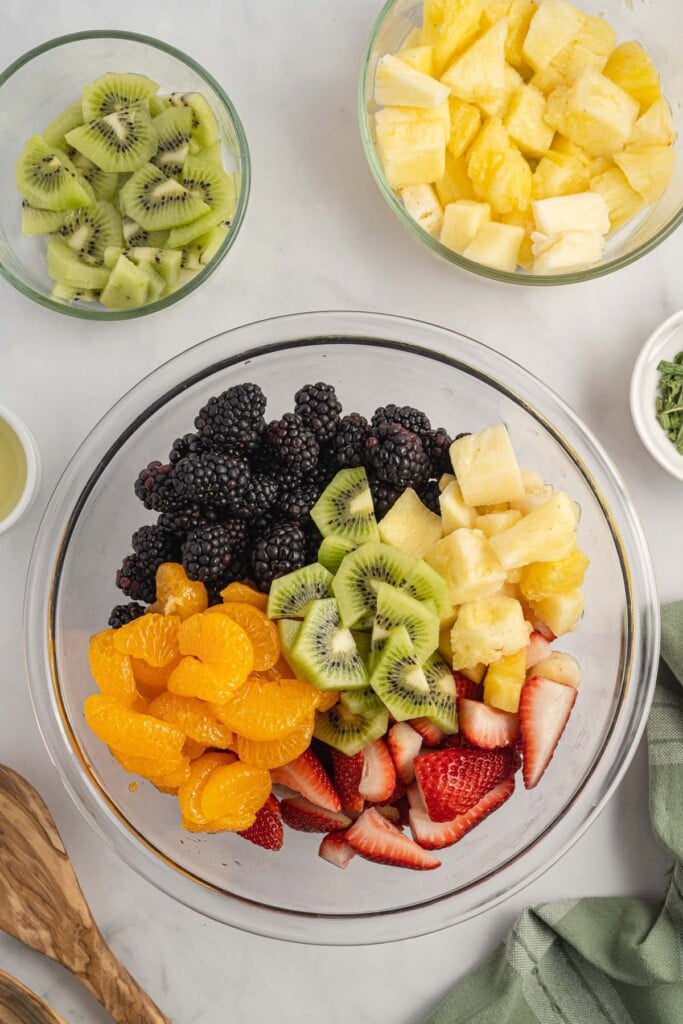 Chopped fruit in a clear bowl before mixing to make a fruit salad.