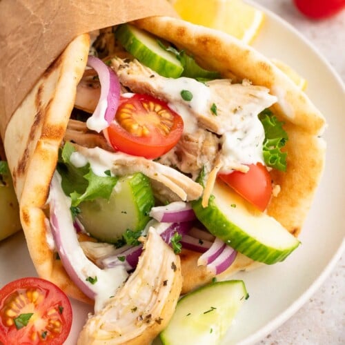 Greek Shredded chicken on a pita with cherry tomatoes and cucumbers.