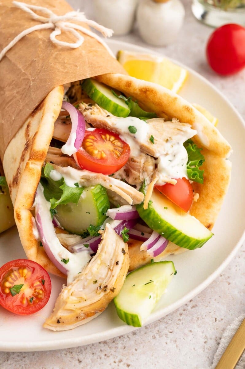 Greek Shredded chicken on a pita with cherry tomatoes and cucumbers.