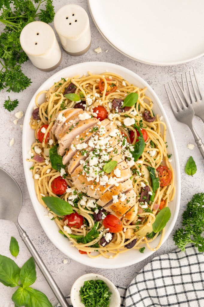 A large white platter of Greek Style Pasta topped with chicken.