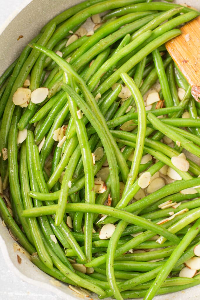 An overhead shot of green beans almondine in a pan