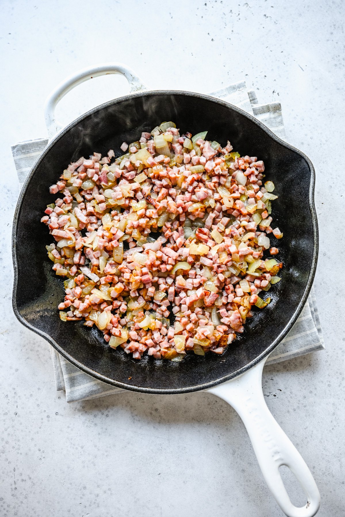 Ham and onions cooking in butter in a cast iron skillet