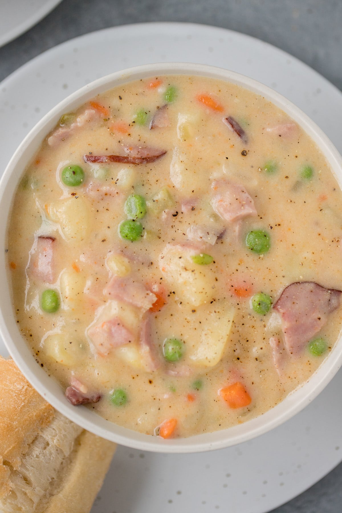 ham and potato soup recipe in a white bowl with bread on the side