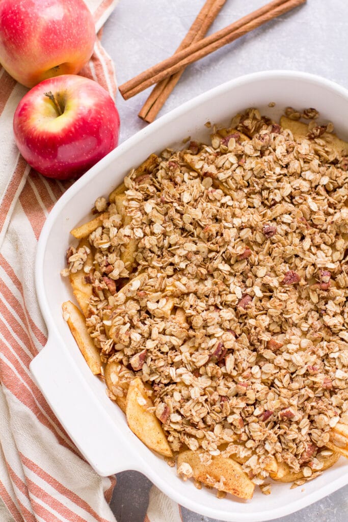 Healthy Apple Crisp in a white baking dish with a red striped linen off to the side